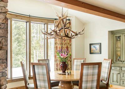 dining room with antler chandelier and plaid chairs of Moonlight residence designed by Elizabeth Robb Interiors